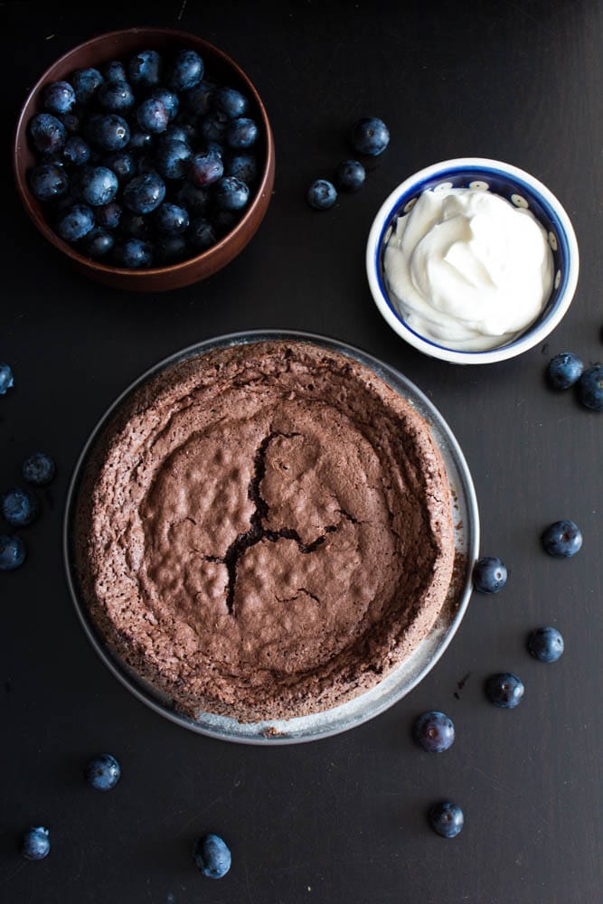 kladdkaka with bowl of cream and bowl of blueberries