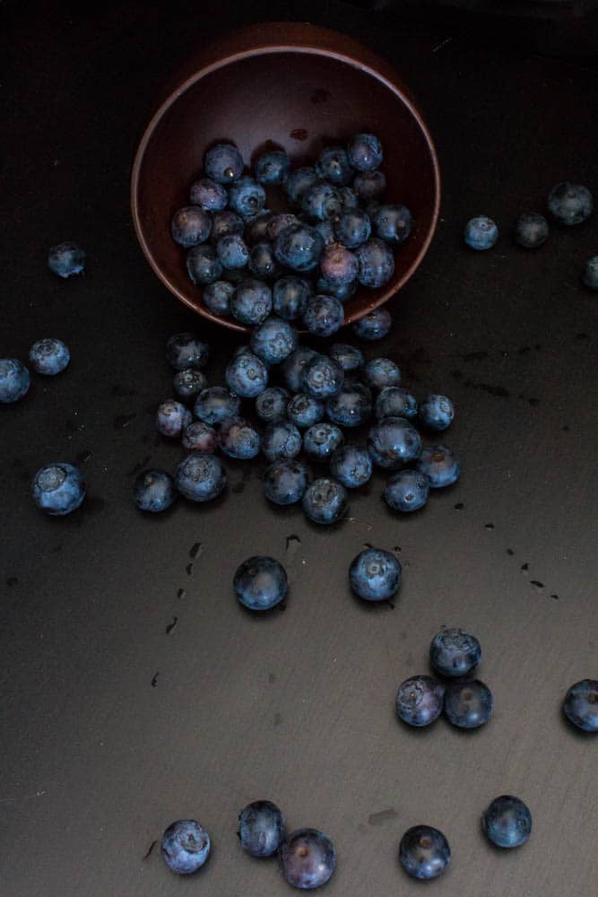 blueberries rolling out of bowl