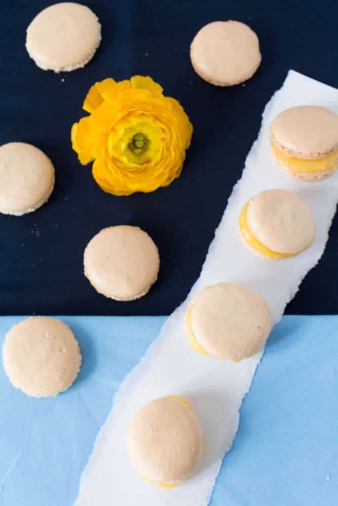 Macarons with pineapple curd on a blue background with yellow peony